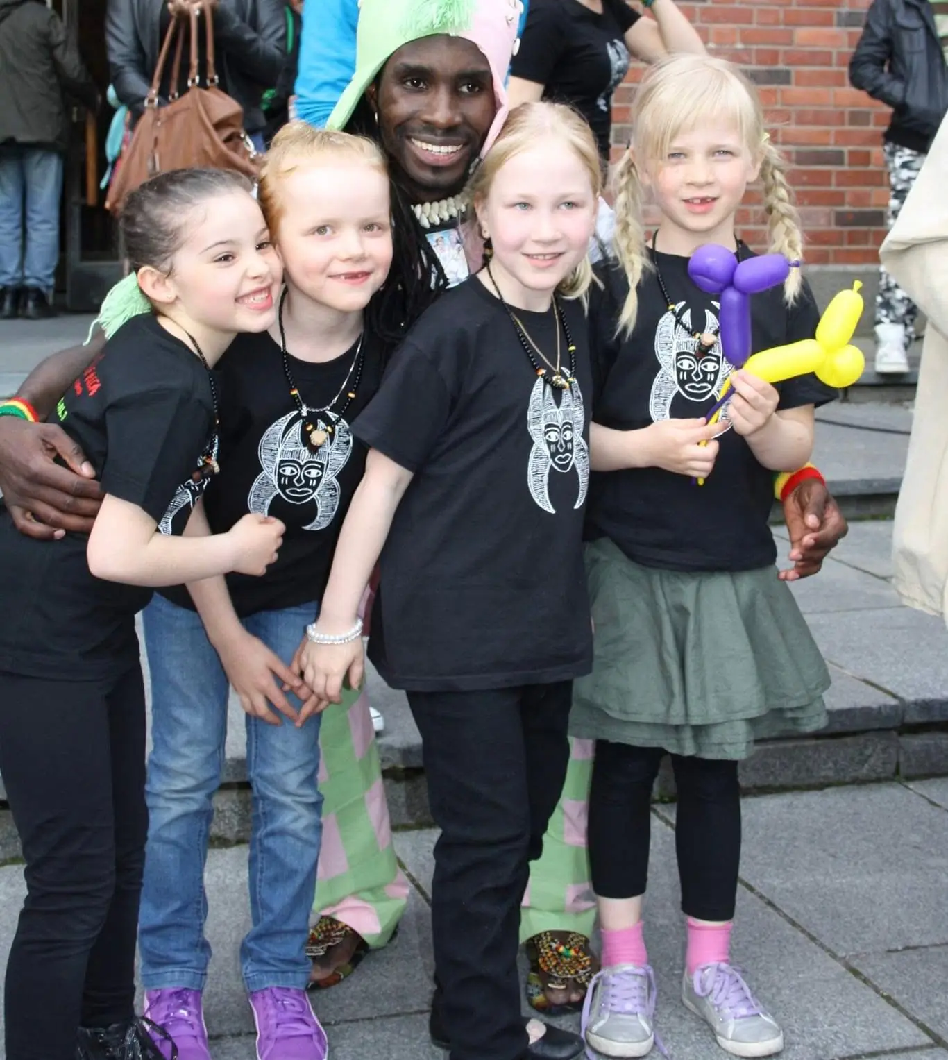 Children in matching T-shirts hug and laugh with a performer