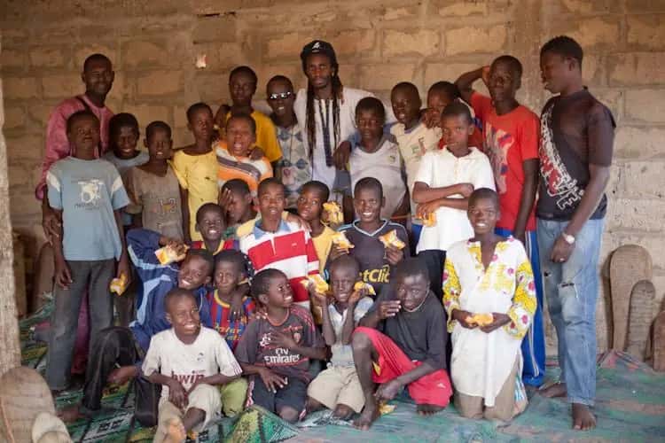 A large group of children and volunteers smile together for a photo
