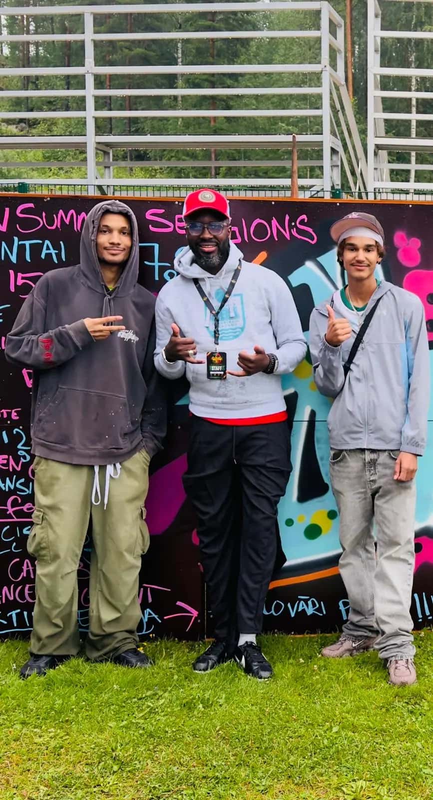 Three artists pose in front of a colourful graffiti wall
