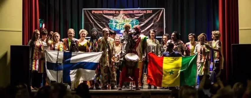 Performers on stage holding the flags of Finland and Senegal