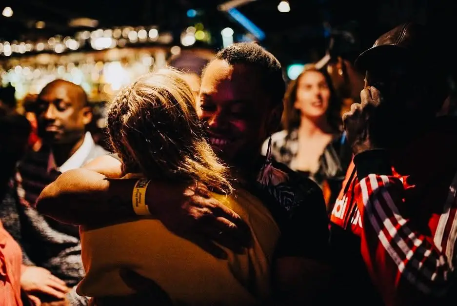 Friends embrace on a busy dance floor