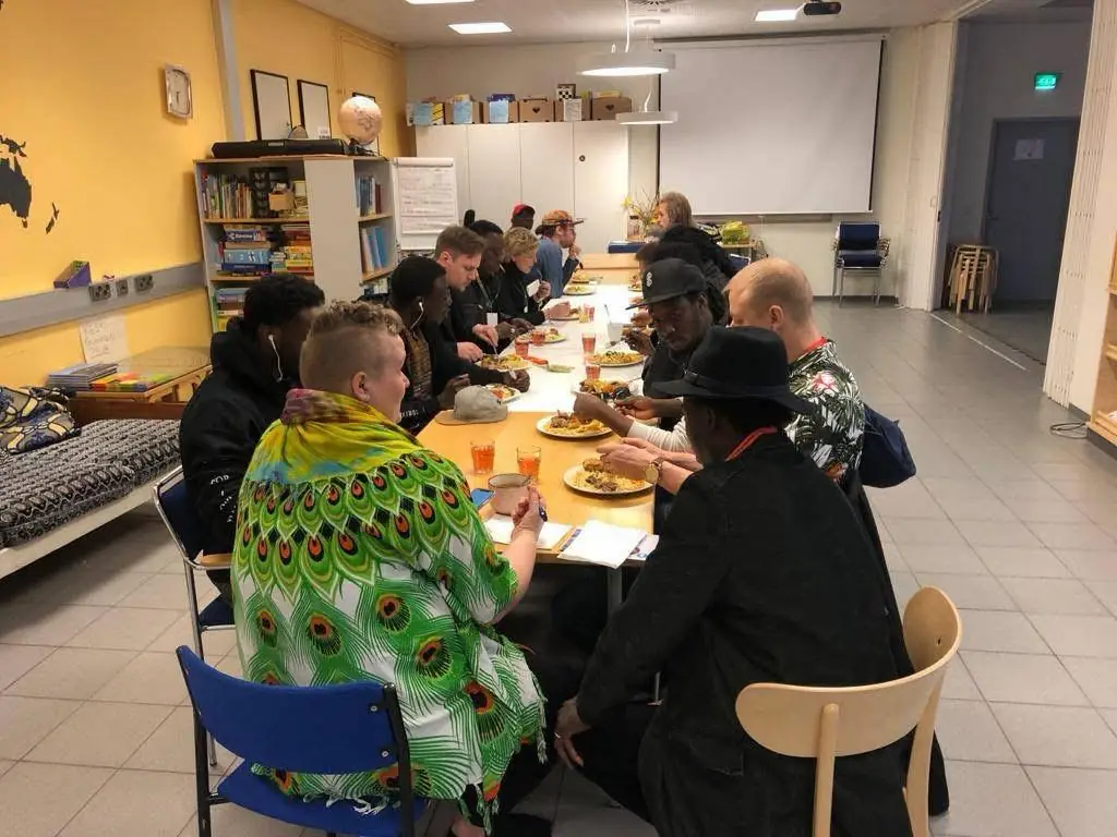 People from different backgrounds share a long community dinner table