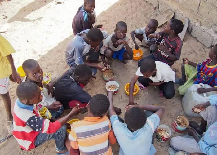 Children sit in a circle sharing a meal