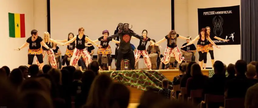 Students perform an African dance routine for a full audience